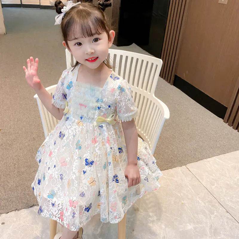 Adorable toddler wearing Solstik girls summer lace gown with floral embroidery and puff sleeves