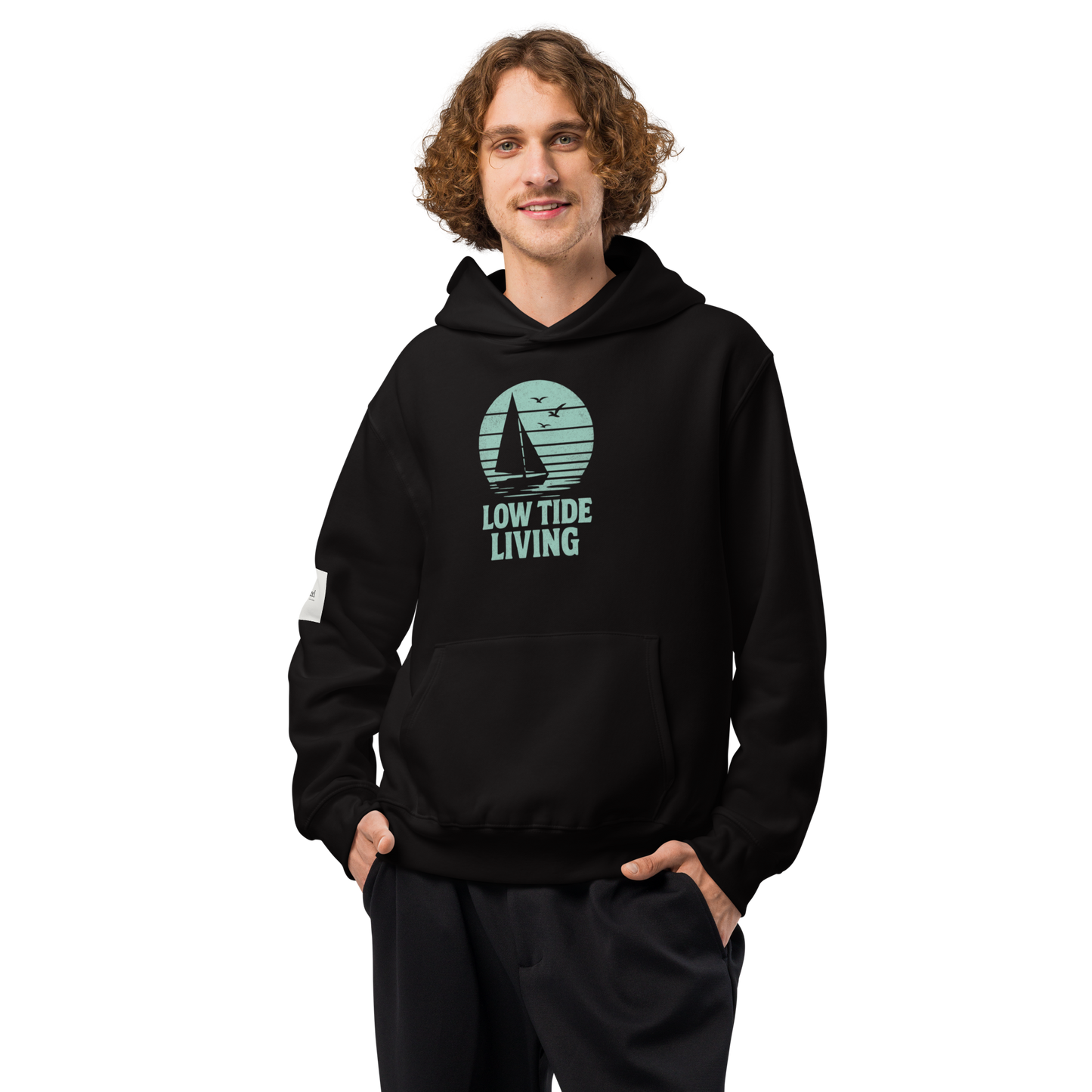 Solstik black Low Tide Living hoodie on model with sailboat graphic and kangaroo pocket premium heavyweight pullover hoodie