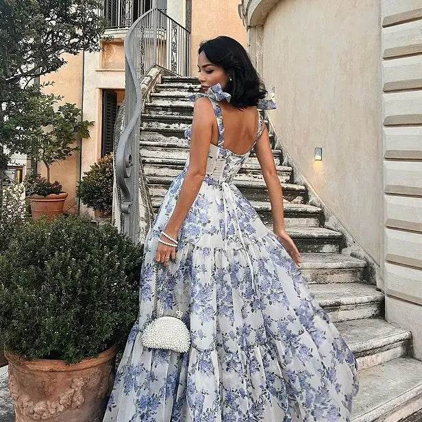 Woman wearing a floral off-shoulder evening gown by Solstik standing near outdoor staircase