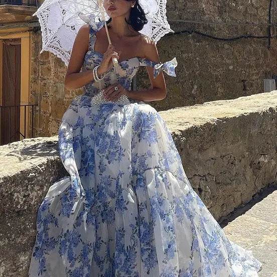 Solstik off-shoulder evening gown with blue floral pattern worn with white lace parasol