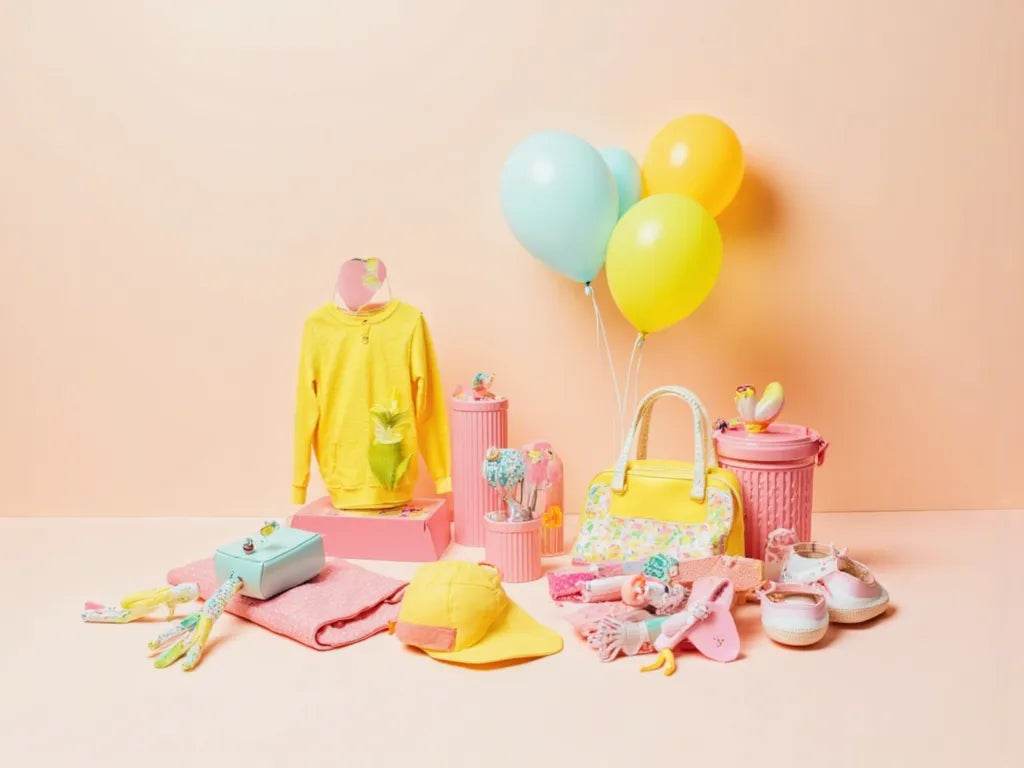 Little Luminaries collection featuring colorful kids clothing, accessories, and playful toys in yellow and pink tones