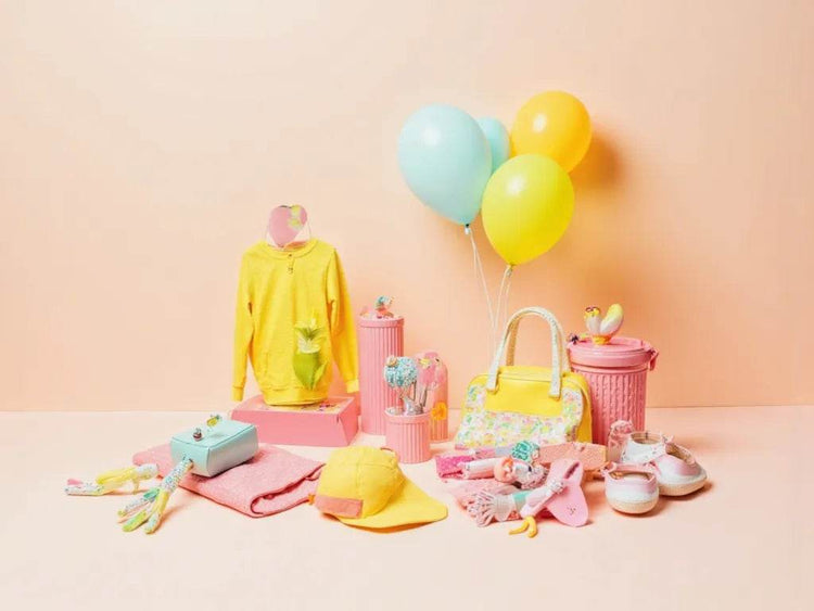 Little Luminaries collection featuring colorful kids clothing, accessories, and playful toys in yellow and pink tones