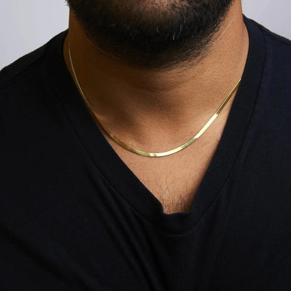 Close up of a man wearing a 14k gold herringbone chain necklace by Aura Jewel Co over a black shirt