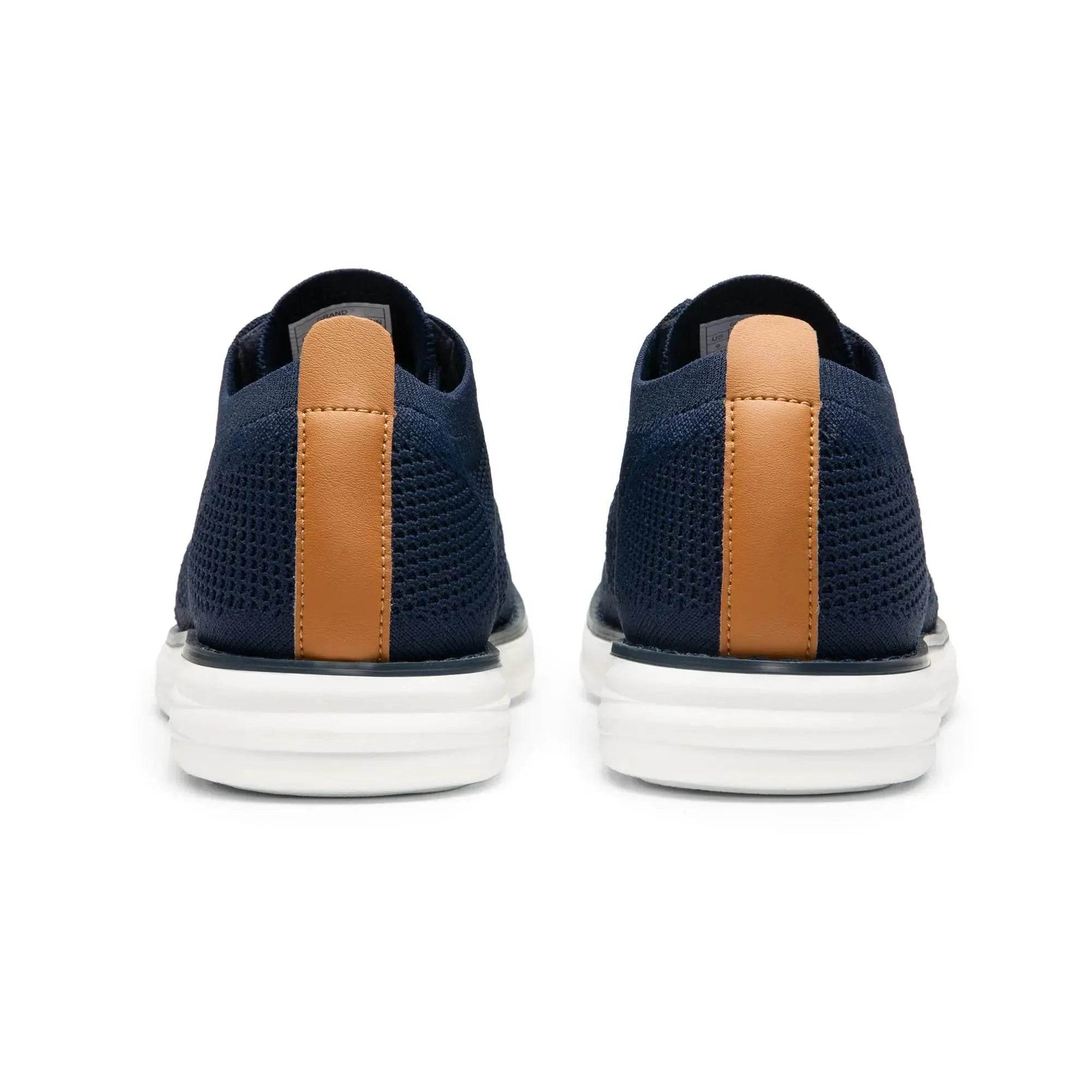 Solstik lightweight men's sneakers in navy blue with white soles and brown heel accents shown from the back