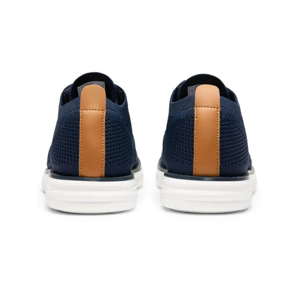 Solstik lightweight men's sneakers in navy blue with white soles and brown heel accents shown from the back