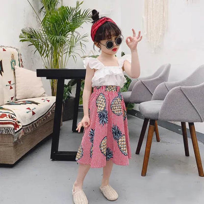 Girls pineapple skirt and top set with red striped skirt and white ruffle top worn by a girl indoors