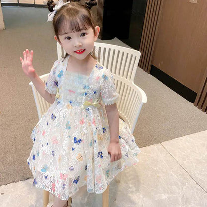 Adorable toddler wearing Solstik girls summer lace gown with floral embroidery and puff sleeves