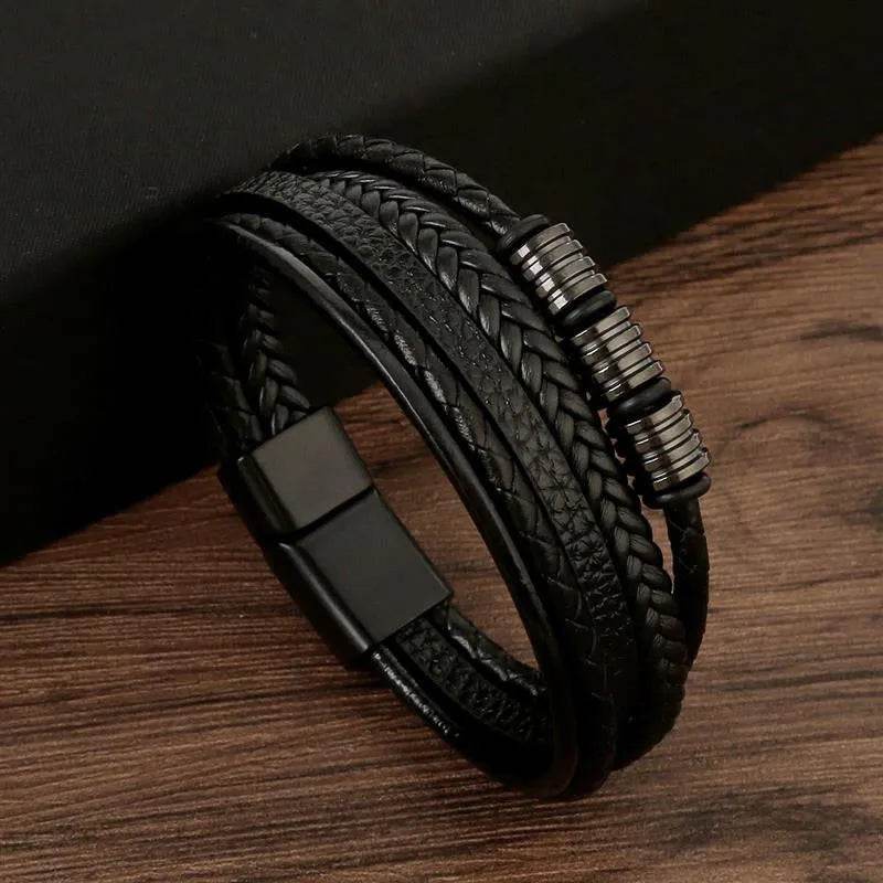 Solstik men's braided leather wristband in black with metal accent and magnetic clasp on wooden surface