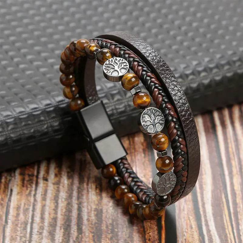Solstik men's braided leather wristband with brown beads and silver tree charms on wooden surface