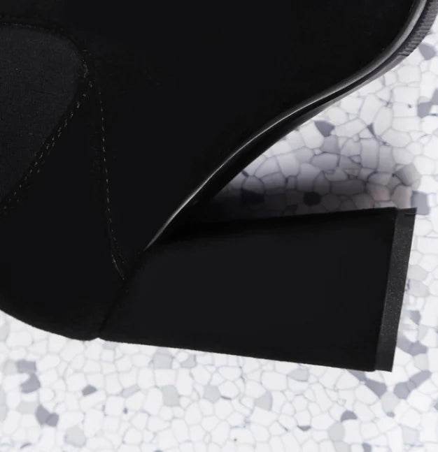 Close-up of black velvet stretch thigh high boots showing block heel and smooth texture