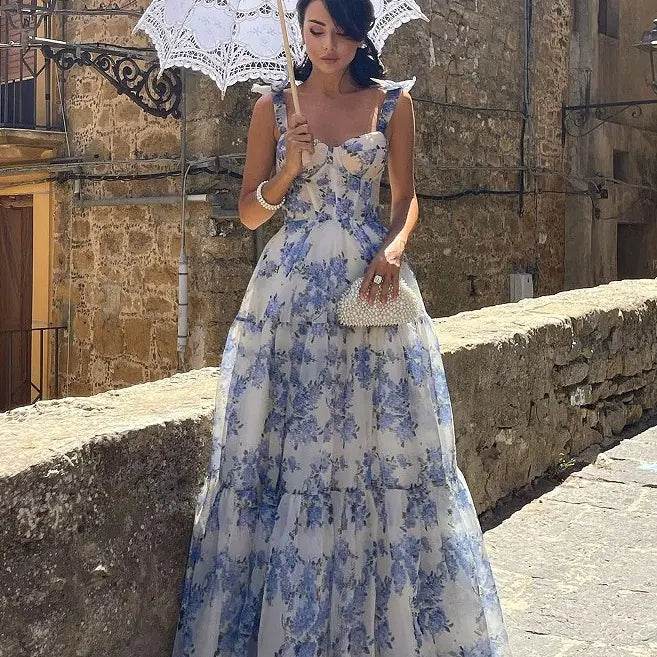 Solstik off-shoulder evening gown with blue floral pattern worn with a white umbrella and clutch